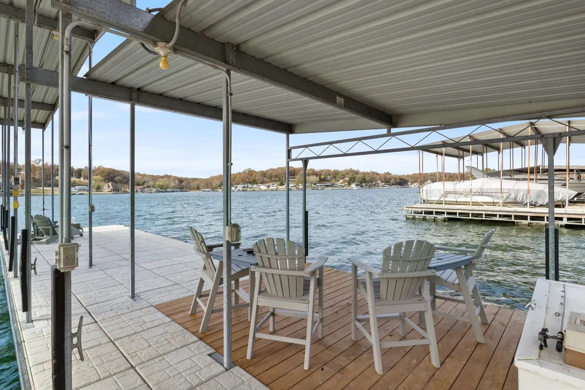 A closer view of the dock, showcasing Adirondack chairs for comfortable seating, the swim platform, and the expansive water beyond. The setup encourages relaxation, socializing, and easy access to swimming, kayaks, and paddleboards.