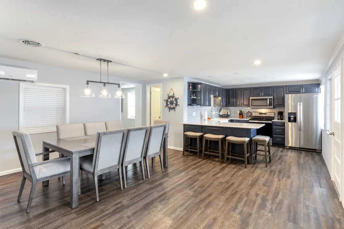A bright, welcoming space that blends a dining table and kitchen island, illuminated by stylish light fixtures. The setting encourages shared meals and social cooking, with the kitchen and dining areas integrated for easy interaction.