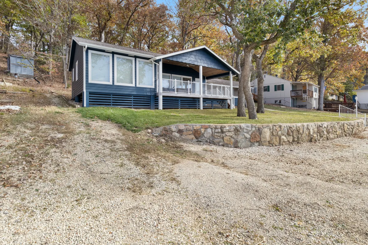 The exterior of the home, featuring a welcoming front porch, large windows, stone wall, and surrounding trees. The inviting entryway suggests security, hospitality, and the seamless arrival experience highlighted in the section.